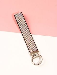 a keychain is sitting on a pink and white surface with a silver ring