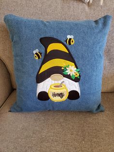 a blue pillow with a bee and honey design on the front sitting on a couch