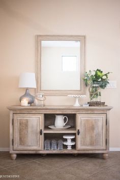 a white vase sitting on top of a wooden cabinet next to a mirror and lamp