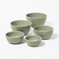 four green bowls sitting next to each other on a white surface