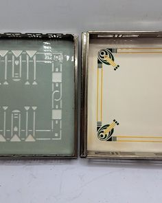 two small tins with designs on them sitting next to each other in metal cases