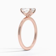 a rose gold engagement ring with a pear shaped diamond center and side stones on the band