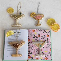 an open book with two ornaments on it and some lemon slices next to it,