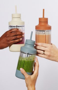 three people are holding blenders with green smoothies in them and one person is holding a shaker