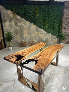 a table made out of wood and glass on top of a tiled floor in front of a stone wall