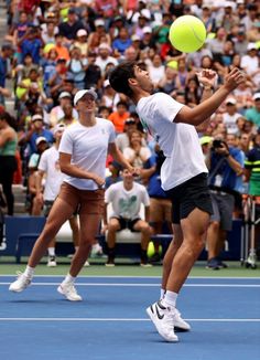 two people playing tennis on a blue court with spectators in the stands watching from behind