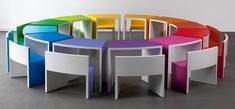 a circular table with multiple colored chairs in the middle and one chair on the other side