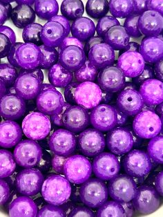 some purple beads are in a white bowl