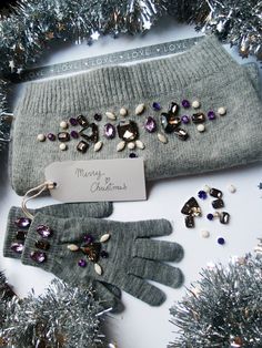 a pair of gray gloves sitting on top of a table next to silver tinsel