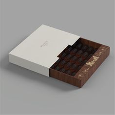 an open box with chocolates inside on a gray background, the packaging is white and brown