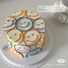 a cake with smiley faces on it sitting on a plate next to a coffee cup