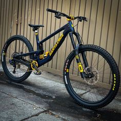 a mountain bike parked in front of a metal building with yellow lettering on it's side