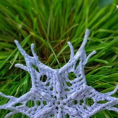 a crocheted snowflake sitting on top of green grass