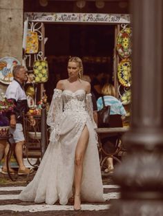 a woman is walking down the street in a white dress