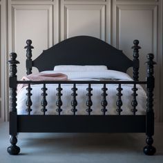 a bed with black headboard and foot board is shown in front of white paneled walls