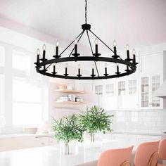 a chandelier hanging from the ceiling in a kitchen with pink chairs around it