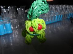 a hand holding a plastic toy with green hair and red eyes in front of some water bottles