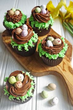 chocolate cupcakes decorated with green icing and mini eggs on a wooden board