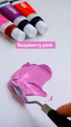 a person is painting some pink paint on a white surface with crayons next to it and the words raspberry pink