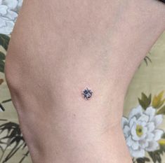 a small tattoo on the back of a woman's lower body, with flowers in the background