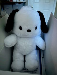 a white stuffed dog sitting inside of a box