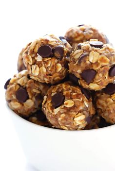 a white bowl filled with chocolate chip granola energy bites on top of a table