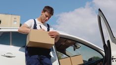 a man loading boxes into the back of a car