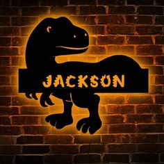 a dinosaur with the name jackson on it is lit up in front of a brick wall