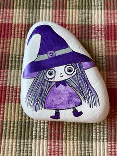 Hand painted on a river rock is a cute quirky witch done in partial metallic purples.  This would make a perfect addition to your Halloween or fall decor. Measures: 3 " x 2 " x 1 ". Sealed with gloss varnish to help preserve the art.   Please note: the back is not painted so that you may see the raw rock. Purple Painted Rocks, River Rock Crafts, Rock People, Witch Painting, Christmas Rock, Turtle Painting, Animal Crafts For Kids, Rock Ideas