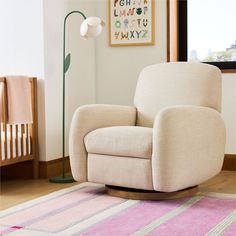 a white chair sitting on top of a wooden floor next to a pink and green rug