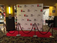 a red carpeted area with a white backdrop and rope barriers in front of it