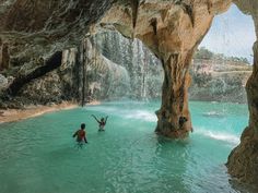 two people are in the water near a cave