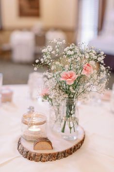 a vase filled with flowers sitting on top of a wooden slice next to a candle