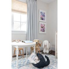 two stuffed animals sitting on the floor in front of a white table with blue rug