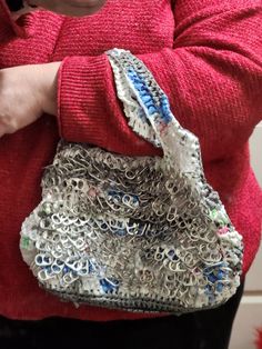 a woman in red sweater holding a silver purse