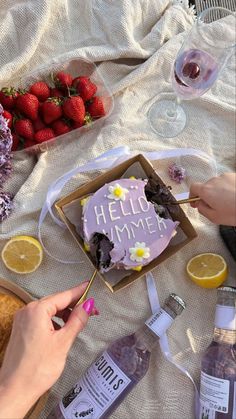 someone is cutting into a cake with strawberries and lemons on the table next to it