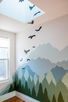 birds flying in the sky above a mountain mural on a wall with wood flooring