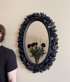 a man standing in front of a mirror with flowers on it