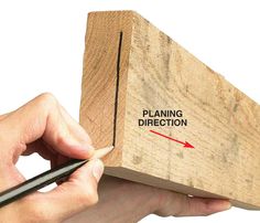 a hand holding a pen and drawing on a piece of wood with the word planning direction