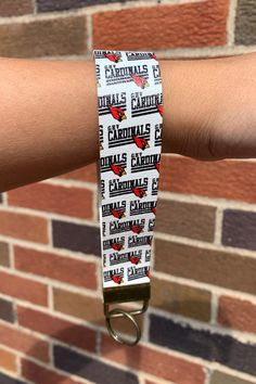 a person's arm with a wristband that has chicago cardinals on it and is holding onto a brick wall