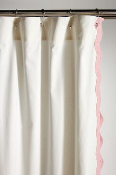 a white curtain with pink scalloped trim