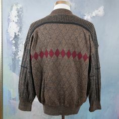 "This 1980s Italian vintage sweater is a warm brown color with a burgundy argyle pattern across the front and back and accented with black fine striping. The wool-mohair blend pullover has a short V neckline with a wide ribbed crossover collar. The sweater has ribbed cuffs and a ribbed waistband. Note that this is a \"short\" size. See especially the sleeve length and sweater length below. Brand label: Nani Bon Size: 46S (US/UK) Material: 40% acrylic, 30% wool, 20% mohair, 10% nylon Chest = 46 i Retro Brown Sweater For Fall, Retro Brown Crew Neck Outerwear, Vintage Brown Cardigan For Winter, Vintage Brown Winter Cardigan, Vintage Brown Long Sleeve Sweater, Vintage Long Sleeve Brown Sweater, Wool Brown Cardigan, Vintage Brown Wool Cardigan, Retro Brown Wool Sweater