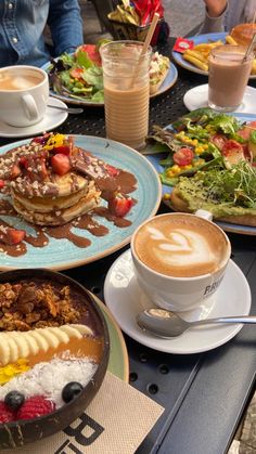 a table topped with plates of food and cups of coffee on top of each other