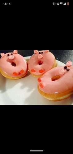 three donuts with pink frosting and pigs on them