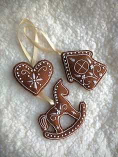 three gingerbread cookies shaped like horses on a white surface with a ribbon around them