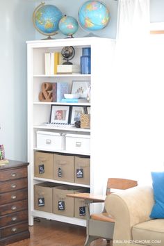 a living room with a white bookcase filled with books and storage bins next to a window