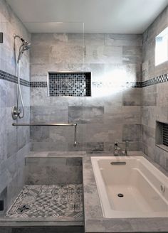 a bathtub and shower in a bathroom with grey tile on the walls, floor and ceiling