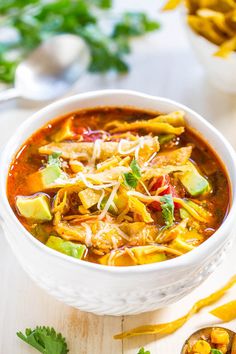 a white bowl filled with chili and tortilla soup on top of a wooden table