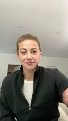 a woman is taking a selfie in the mirror with her cell phone and wearing a black jacket