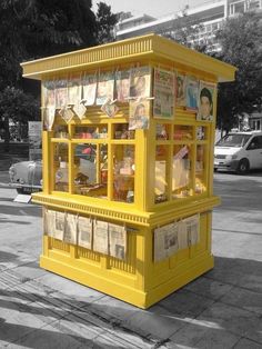 a yellow kiosk sitting on the side of a road